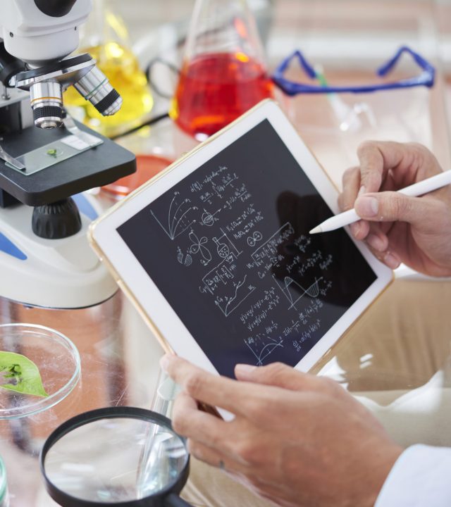 Scientist drawing chemical formulas and making calculations on tablet computer